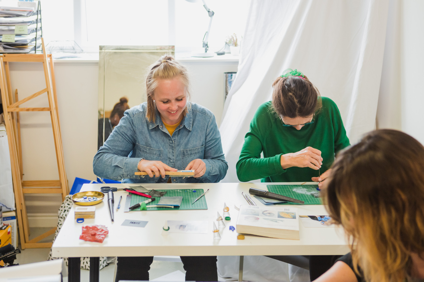Two women sit side by side at a jewellery making class